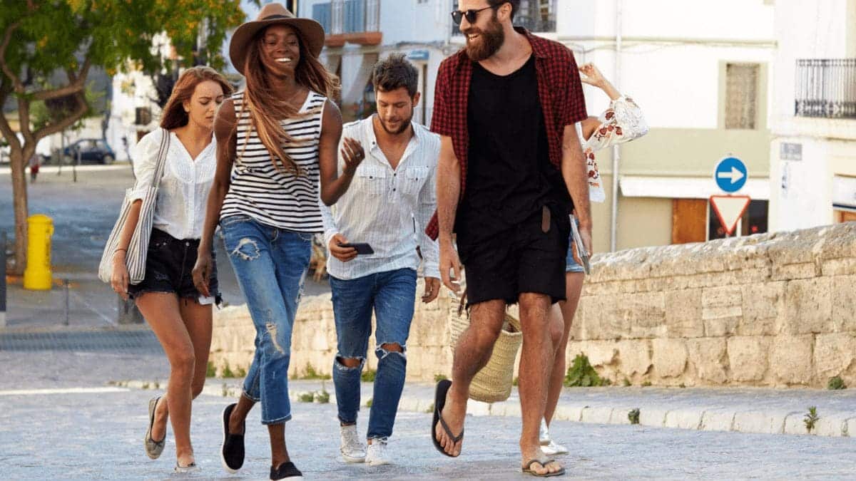 Group of young people walking on a vacation booked through a travel rewards program.