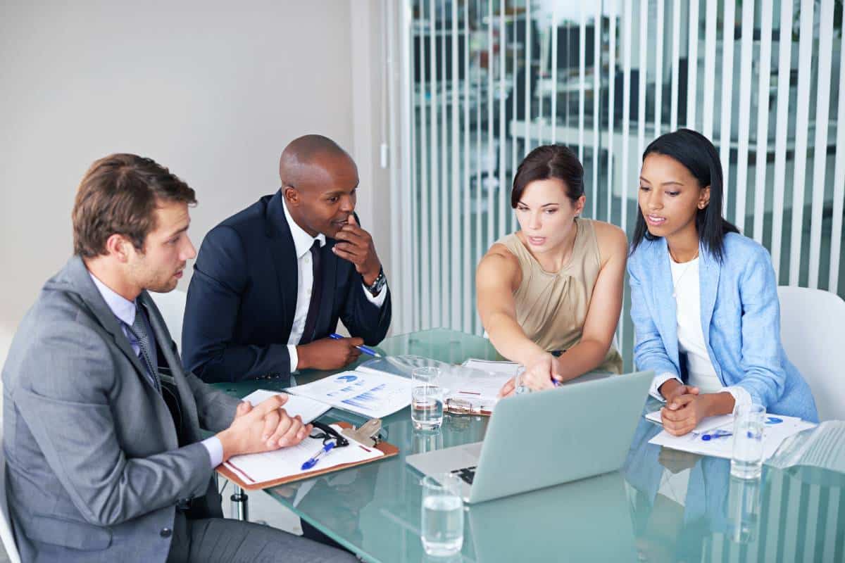 A team of professionals discussing data on a laptop, focusing on turning loyalty data into insights.