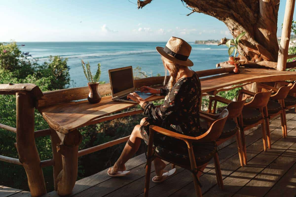 A woman works on her laptop overlooking the ocean, enjoying the enhanced user experience of a loyalty rewards program.
