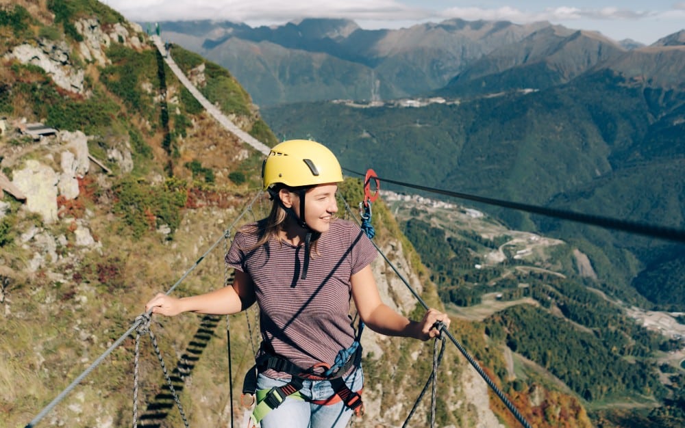  A young woman enjoys a thrilling suspension bridge walk in the mountains