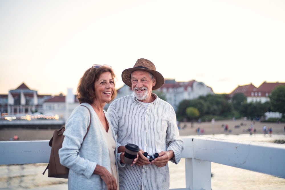 An older couple smiling and enjoying a seaside stroll