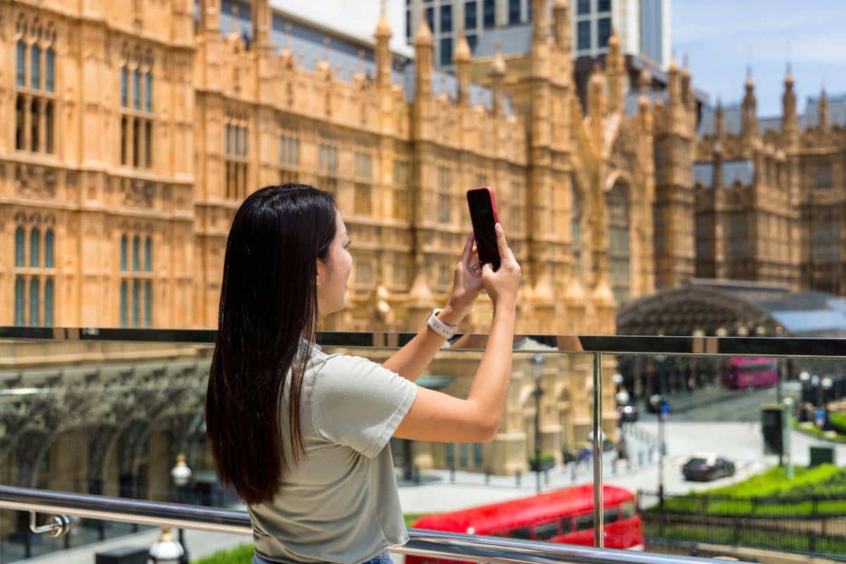 Tourist utilizing augmented reality in travel & tourism on her smartphone to explore a city landmark.