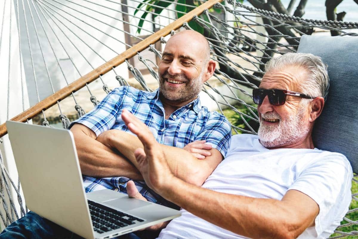 Two older men in a hammock with a laptop, taking a survey to gather customer loyalty data.