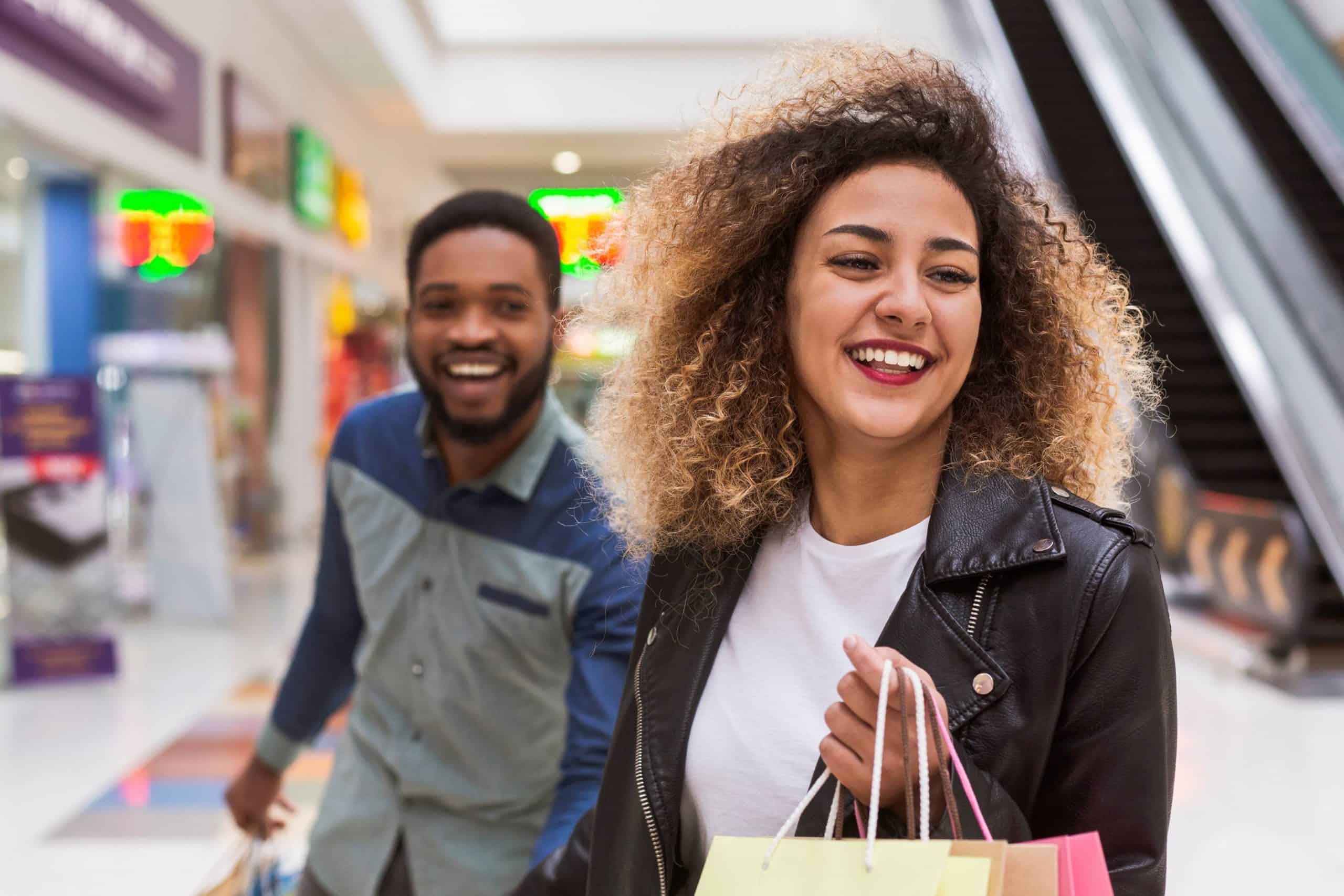 A happy couple walks through a shopping mall with bags in hand