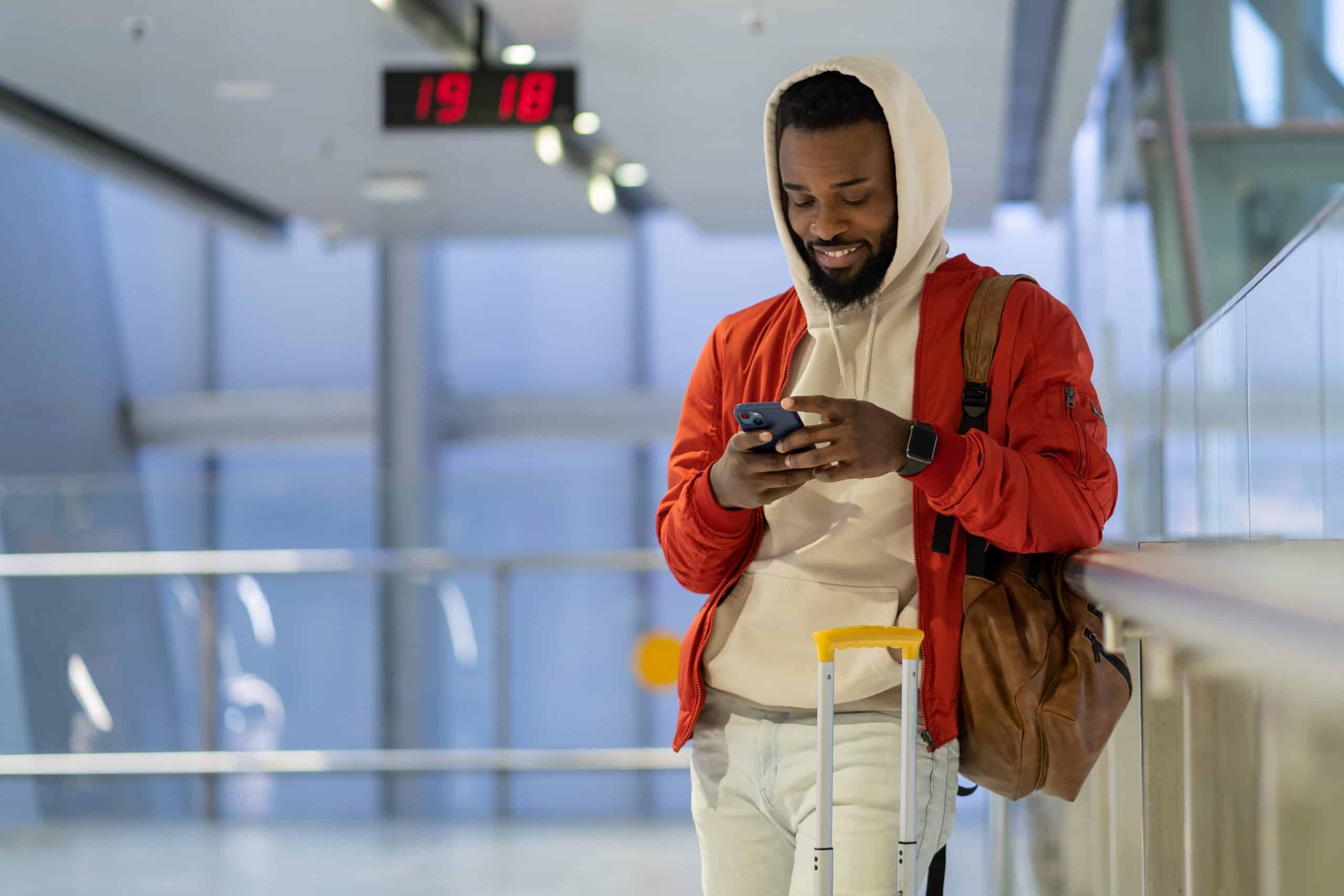 A man with a suitcase engages with his loyalty program while traveling