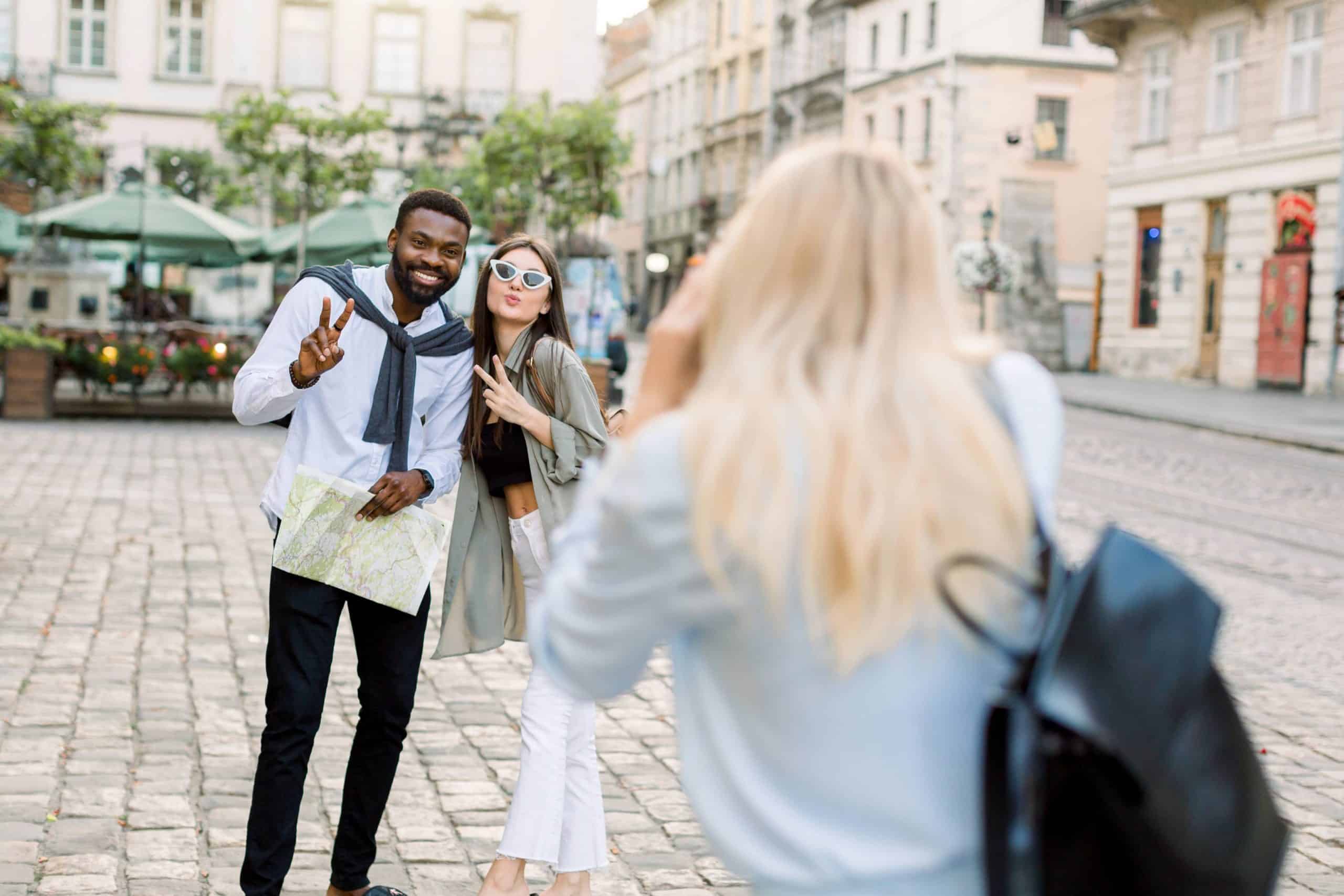 Two friends strike playful poses for a picture on a cobblestone street during their travels.